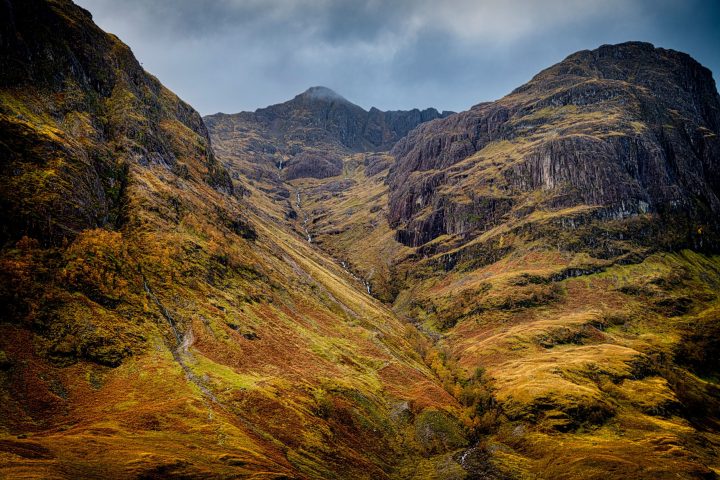 A Highland glen with steep golden-brown hillsides under cloud
